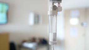 Close-up of saline solution drip for patient and infusion pump on blurred luxury VIP room background in hospital.