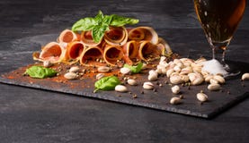 Close-up of sliced jamon and a glass of beer on a black table background. Salted pistachios and fresh basil on a wooden stock image Close-up of sliced jamon and a glass of beer on a black table background. Salted pistachios and fresh basil on a wooden stock image
