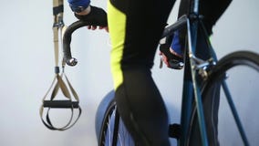 Close-up of sportsman legs working out on bicycle indoors in the gym.