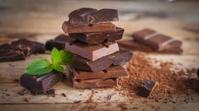 Close-up of stacked dark and milk chocolate with fresh mint, on wooden background stock image Close-up of stacked dark and milk chocolate with fresh mint, on wooden background stock image