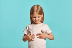Close-up studio shot of a lovely blonde little girl in a white t-shirt posing against a blue background. stock photography Close-up studio shot of a lovely blonde little girl in a white t-shirt posing against a blue background. stock photography
