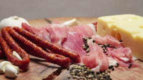 Close up of thin slices of prosciutto with dry raw sausages and swiss cheese on wooden cutting board stock video footage Close up of thin slices of prosciutto with dry raw sausages and swiss cheese on wooden cutting board stock video footage