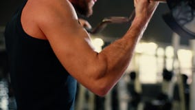 Close-up of unrecognizable young man with muscular wiry body lifting barbell.