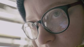 Close-up van vrouwenogen wordt geschoten in glazen die op het scherm dat van een werkende smartphone wijzen stock footage Close-up van vrouwenogen wordt geschoten in glazen die op het scherm dat van een werkende smartphone wijzen stock footage