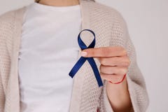 Close up view of blue ribbon in the female hand. Colon cancer. stock photos Close up view of blue ribbon in the female hand. Colon cancer. stock photos