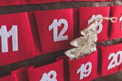 Close up view of a red and brown textile Advent calendar with dates and a Christmas tree decoration in a pocket stock image Close up view of a red and brown textile Advent calendar with dates and a Christmas tree decoration in a pocket stock image