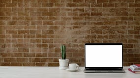Close Up View Of Workplace With Mock Up Laptop , Office Supplies, Decorations And Copy Space On White Desk With Brick Wall Stock Photography