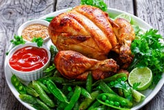 Close-up of a whole roast chicken with peas