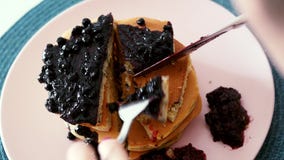 Close-up of woman eating berries pancakes with knife and fork, morning breakfast stock video Close-up of woman eating berries pancakes with knife and fork, morning breakfast stock video