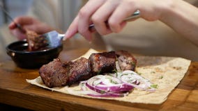 Close up woman`s hands with knife and fork cutting meat in dish on table in a restaurant stock footage Close up woman`s hands with knife and fork cutting meat in dish on table in a restaurant stock footage