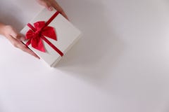 Close-up women hands sending white gift box with red ribbon on white background royalty free stock images Close-up women hands sending white gift box with red ribbon on white background royalty free stock images