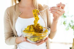 Worried cute woman holding bowl with measuring tapes at home royalty free stock photo Worried cute woman holding bowl with measuring tapes at home royalty free stock photo