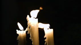 Close-uplengte van drie witte lange en in brand gestoken kaarsen die in weinig pogingen worden geblazen stock footage Close-uplengte van drie witte lange en in brand gestoken kaarsen die in weinig pogingen worden geblazen stock footage
