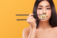 Close-upportret van Aziatische vrouw die sushi en broodjes op een gele achtergrond eten Copyspace royalty-vrije stock afbeelding Close-upportret van Aziatische vrouw die sushi en broodjes op een gele achtergrond eten Copyspace royalty-vrije stock afbeelding