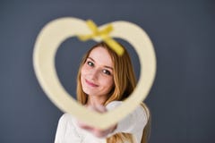 Close-upportret van de jonge vrouwelijke die vorm van het holdingshart op grijze achtergrond wordt geïsoleerd stock afbeelding Close-upportret van de jonge vrouwelijke die vorm van het holdingshart op grijze achtergrond wordt geïsoleerd stock afbeelding