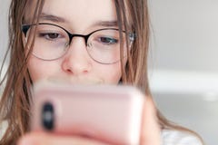 Close-upportret van leuk gelukkig tween meisje die in glazen smartphone in haar handen bekijken stock fotografie Close-upportret van leuk gelukkig tween meisje die in glazen smartphone in haar handen bekijken stock fotografie