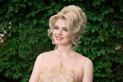 Close-upportret van leuke glimlachende vrouw op een achtergrond die van aard, een beige kleding dragen Het bekijken u camera Posi royalty-vrije stock foto Close-upportret van leuke glimlachende vrouw op een achtergrond die van aard, een beige kleding dragen Het bekijken u camera Posi royalty-vrije stock foto