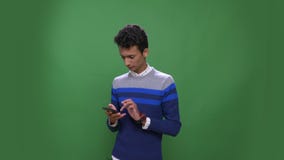 Close-upspruit van jong aantrekkelijk Indisch mannetje die de telefoon met achtergrond met behulp van die op groen wordt ge?solee stock footage Close-upspruit van jong aantrekkelijk Indisch mannetje die de telefoon met achtergrond met behulp van die op groen wordt ge?solee stock footage