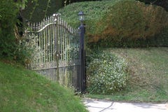 Closed iron driveway gates surrounded by shrubbery Stock Photo Closed iron driveway gates surrounded by shrubbery Stock Photo