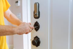 Closeup av en yrkesmässig låssmed som installerar eller reparerar ett nytt deadboltlås arkivbild Closeup av en yrkesmässig låssmed som installerar eller reparerar ett nytt deadboltlås arkivbild