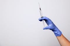 Closeup doctor or nurse hand in rubber latex medical purple glove holding a transparent syringe with sharp needle. Сoncept royalty free stock photography Closeup doctor or nurse hand in rubber latex medical purple glove holding a transparent syringe with sharp needle. Сoncept royalty free stock photography