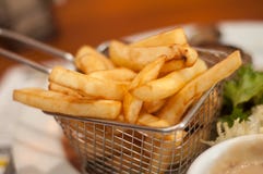 French fries in little metallic basket in a plate at. Closeup of french fries in little metallic basket in a plate at restaurant Royalty Free Stock Photos French fries in little metallic basket in a plate at. Closeup of french fries in little metallic basket in a plate at restaurant Royalty Free Stock Photos