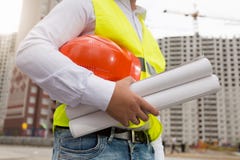 Closeup image of male engineer holding blueprints of new house and red hardhat stock image Closeup image of male engineer holding blueprints of new house and red hardhat stock image