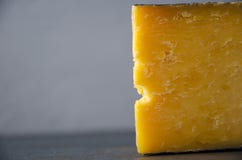 Closeup of piece of gouda on dark table against grey wall royalty free stock images Closeup of piece of gouda on dark table against grey wall royalty free stock images