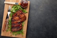 Closeup of pork ribs grilled with BBQ sauce and caramelized in honey on a bed of arugula. Tasty snack to beer on a royalty free stock photo Closeup of pork ribs grilled with BBQ sauce and caramelized in honey on a bed of arugula. Tasty snack to beer on a royalty free stock photo