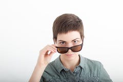 Closeup portrait of a beautiful young woman on white background with dark short hair looking over sunglasses. stock photo Closeup portrait of a beautiful young woman on white background with dark short hair looking over sunglasses. stock photo