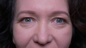 Closeup portrait of old caucasian brunette female face with eyes looking at camera with background isolated on green stock footage Closeup portrait of old caucasian brunette female face with eyes looking at camera with background isolated on green stock footage