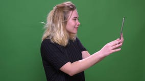 Closeup portrait of young pretty blonde caucasian female having a video call on the tablet with background isolated on stock video Closeup portrait of young pretty blonde caucasian female having a video call on the tablet with background isolated on stock video