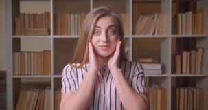 Closeup portrait of young pretty caucasian female student smiling with excitement looking at camera in the college stock footage Closeup portrait of young pretty caucasian female student smiling with excitement looking at camera in the college stock footage