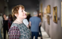Closeup på den uppmärksamma höga kvinnan som besöker museet och tycker om a arkivbild Closeup på den uppmärksamma höga kvinnan som besöker museet och tycker om a arkivbild