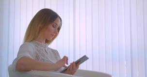 Closeup side view portrait of young pretty caucasian businesswoman using the tablet smiling happily looking at camera stock video Closeup side view portrait of young pretty caucasian businesswoman using the tablet smiling happily looking at camera stock video
