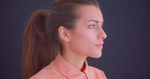 Closeup side view portrait of young pretty caucasian female looking forward and turning to camera with background stock footage Closeup side view portrait of young pretty caucasian female looking forward and turning to camera with background stock footage