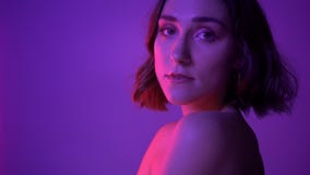 Closeup side view shoot of young alluring female posing and fixing her hair in front of the camera with neon purple stock video Closeup side view shoot of young alluring female posing and fixing her hair in front of the camera with neon purple stock video