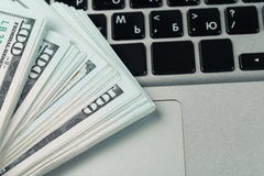 Closeup view of one hundred dollar banknotes lying on the laptop keyboard stock photography Closeup view of one hundred dollar banknotes lying on the laptop keyboard stock photography
