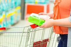 Closeup of woman hands with an item and shopping cart in supermarket. Shopping concept stock images Closeup of woman hands with an item and shopping cart in supermarket. Shopping concept stock images