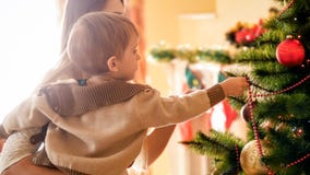 Closeupfoto av den förtjusande pysen som sätter garneringar på det Chrismtas trädet royaltyfria bilder Closeupfoto av den förtjusande pysen som sätter garneringar på det Chrismtas trädet royaltyfria bilder