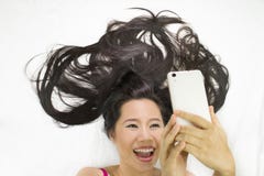CloseupstÃ¥ende av asiatiska kvinnor som ligger pÃ¥ jordning med svart lÃ¥ngt hÃ¥r agera överraska, och plying av telefonen royaltyfri foto CloseupstÃ¥ende av asiatiska kvinnor som ligger pÃ¥ jordning med svart lÃ¥ngt hÃ¥r agera överraska, och plying av telefonen royaltyfri foto