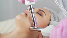 Clínica da beleza Uma mulher obtém a beleza o procedimento facial da cosmetologia video estoque Clínica da beleza Uma mulher obtém a beleza o procedimento facial da cosmetologia video estoque