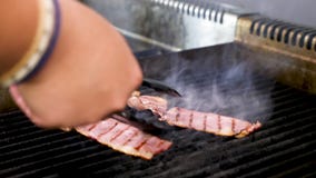 Cocine el turnin de las manos dos pedazos de tocino ahumado en la parrilla metrajes Cocine el turnin de las manos dos pedazos de tocino ahumado en la parrilla metrajes