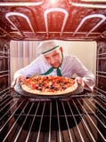 Cocinero que cocina la pizza en el horno fotografía de archivo libre de regalías Cocinero que cocina la pizza en el horno fotografía de archivo libre de regalías