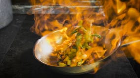 Cocinero que fríe vehículos El coñac se enciende en la cacerola Abra el fuego en la cocina Cocinero que fríe vehículos El coñac se enciende en la cacerola Abra el fuego en la cocina