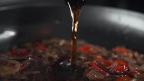 Cocinero que hace la salsa con la cerveza y verduras, pimienta de chile y cebolla en el sartén, el cocinar de la comida Cocinero que hace la salsa con la cerveza y verduras, pimienta de chile y cebolla en el sartén, el cocinar de la comida