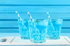Cocktail bleu avec de la glace et la menthe en verres sur un conseil en bois blanc sur une table bleue images stock Cocktail bleu avec de la glace et la menthe en verres sur un conseil en bois blanc sur une table bleue images stock