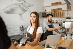 Coffee Business Concept - Beautiful Female Barista Giving Payment Service For Customer With Credit Card And Smiling Stock Photography