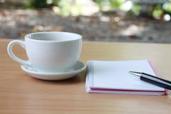 Coffee cup and notebook pen are placed on a brown wooden table a stock photos Coffee cup and notebook pen are placed on a brown wooden table a stock photos