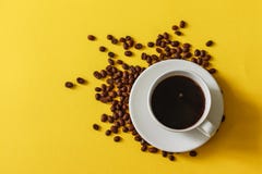 Hot cup of coffee with scattered beans on a yellow background stock photos Hot cup of coffee with scattered beans on a yellow background stock photos